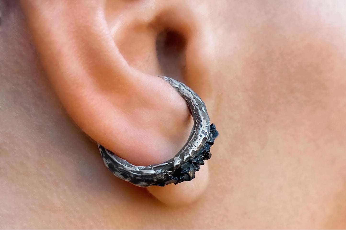 Close-up of a silver hoop earring worn on an ear