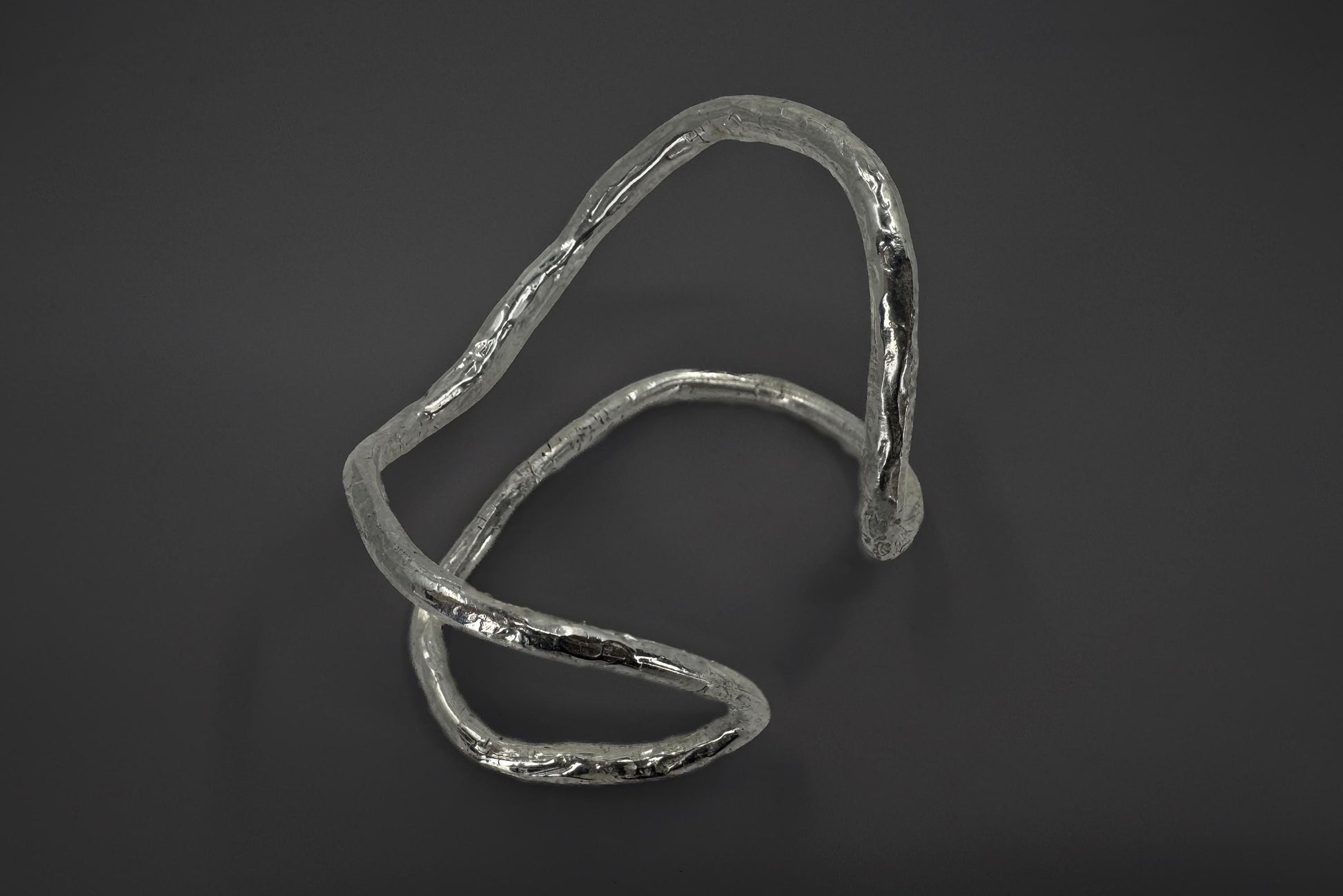 Sterling silver palm bracelet with a wavy design on a dark background