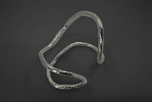 Sterling silver palm bracelet with a wavy design on a dark background