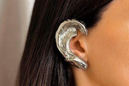 Sterling Silver wave shaped wrap earring worn by a person with dark hair.