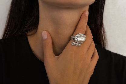 Close-up of a hand wearing a sterling silver ring with a pearl, touching the neck.