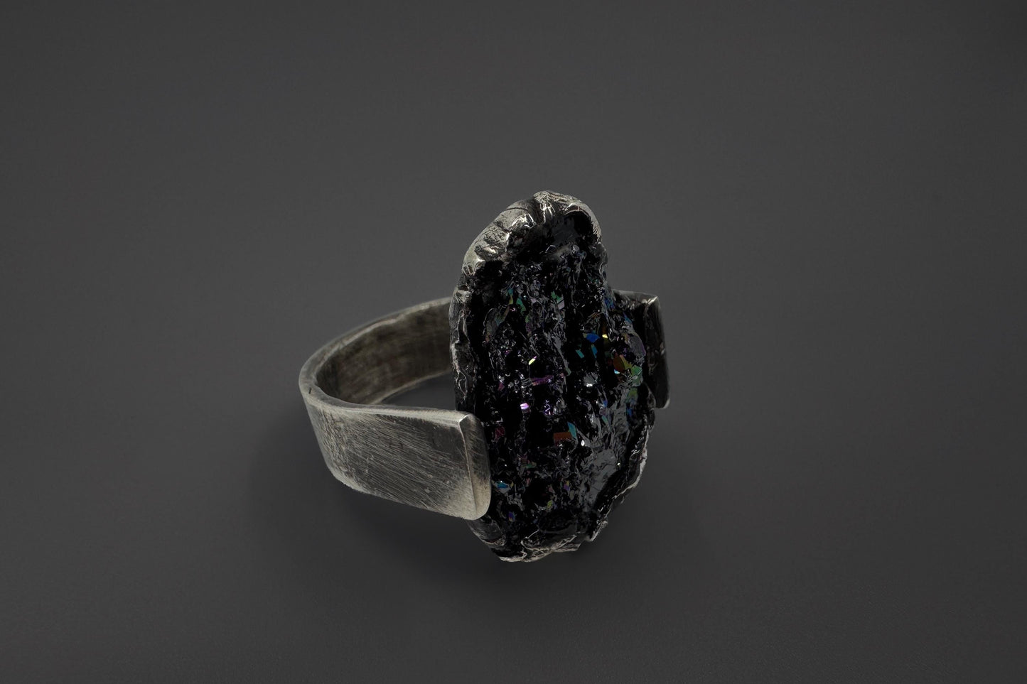 Silver ring with a dark stone on a black background
